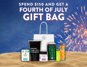 Fourth of July Gift Bag Event: bag contents sit on sand in front of fireworks